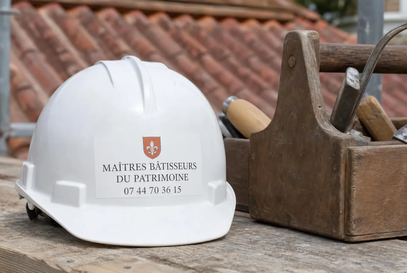 Casque et caisse à outils de couvreur marqués Maîtres Bâtisseurs du Patrimoine sur un chantier à Draguignan