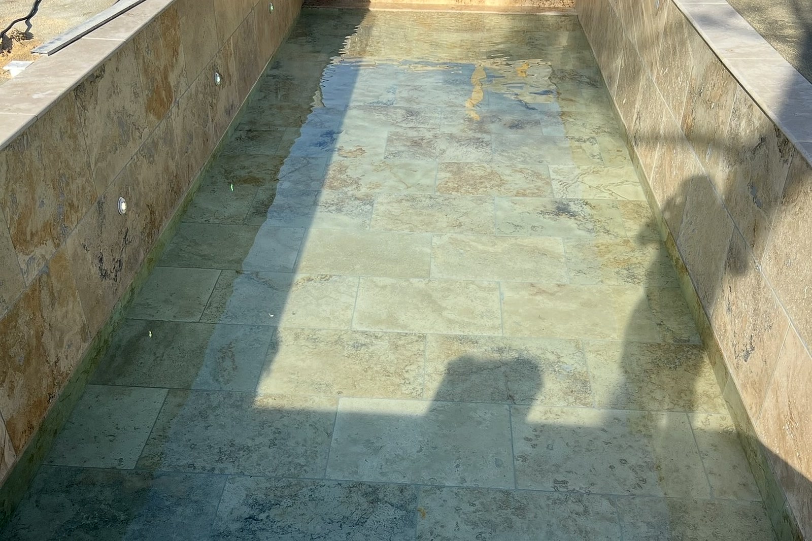 Piscine en travertin remplie d'eau avec couloir de nage dans le Var