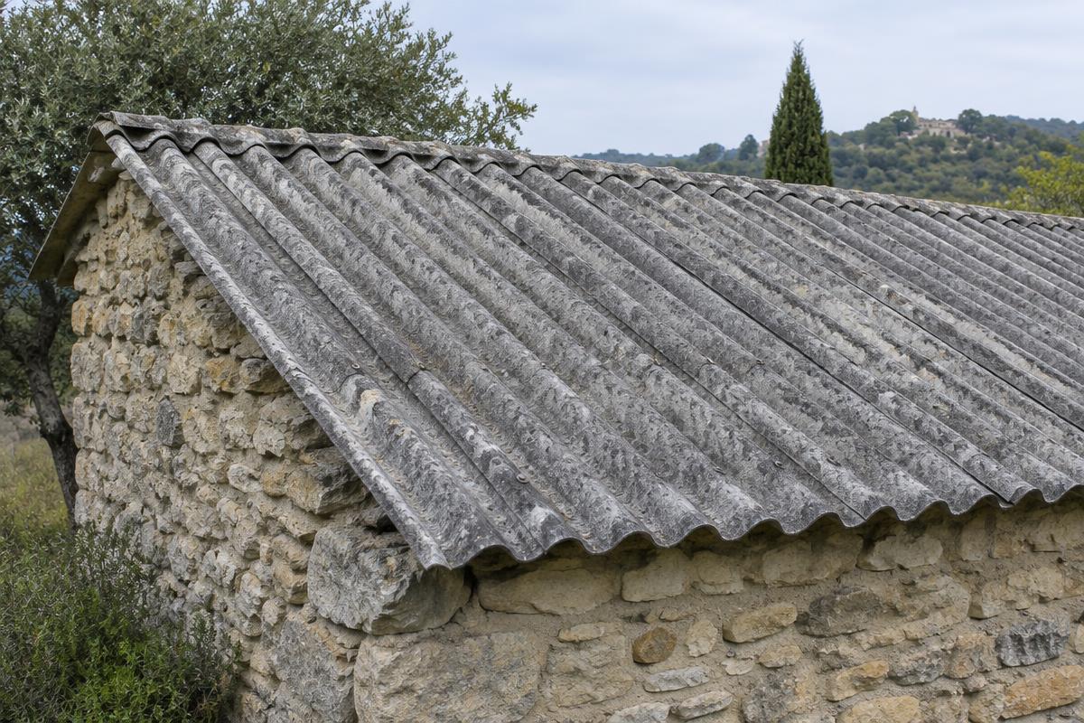Illustration d’une couverture ancienne en plaques ondulées de fibrociment sur un bâtiment en pierre en Provence