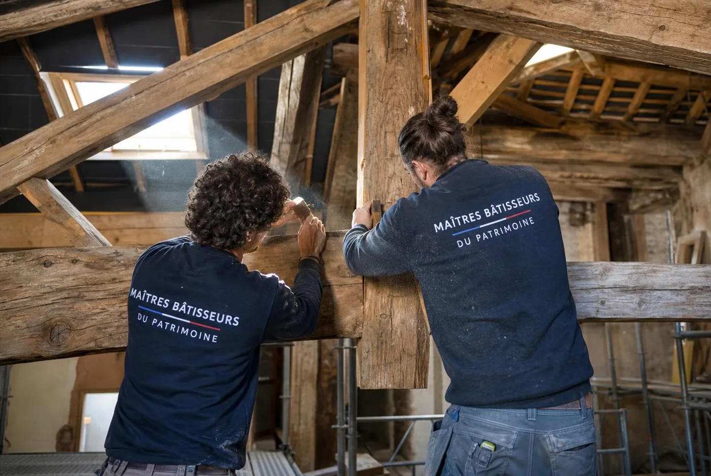 Traitement et reprise d'une charpente ancienne en chêne à Marseille par deux artisans en pull d'atelier