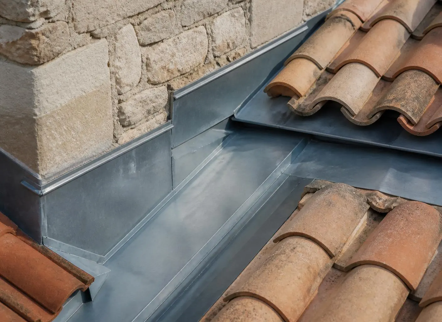 Détail de zinguerie façonnée à la main sur une toiture provençale